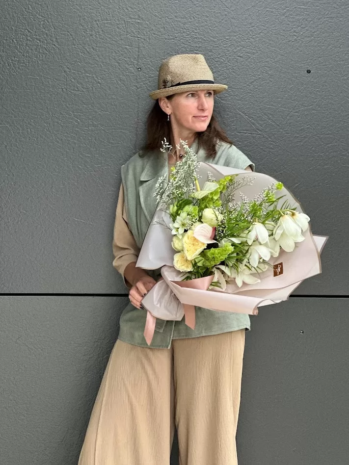 Sieviete ar elegantu ziedu pušķi maigos pasteļtoņos