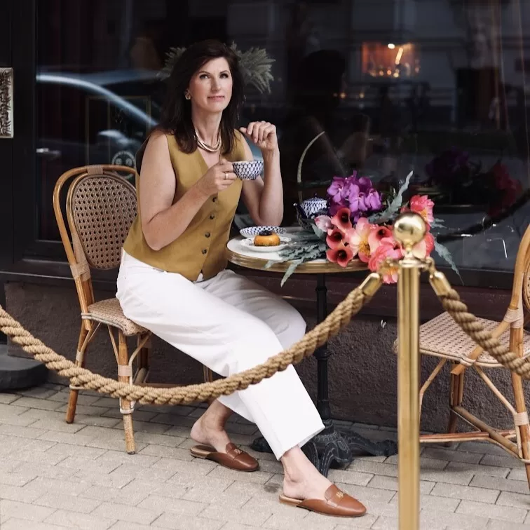 Sieviete pie dekorēta galda ar ziedu kompozīciju restorāna terasē