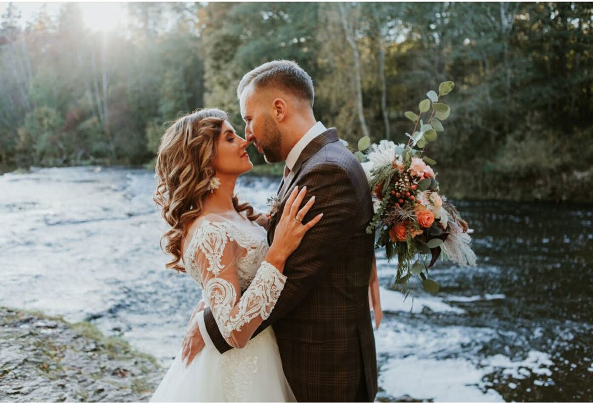 Bride and groom with the bridal bouquet taking photos in nature by the water