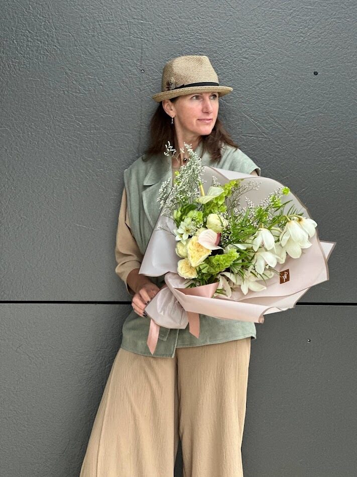 Sieviete ar elegantu ziedu pušķi maigos pasteļtoņos