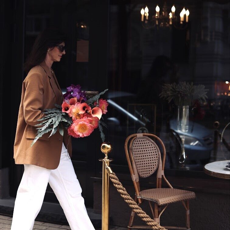 An elegant woman carries pink peony flowers and calla lilies
